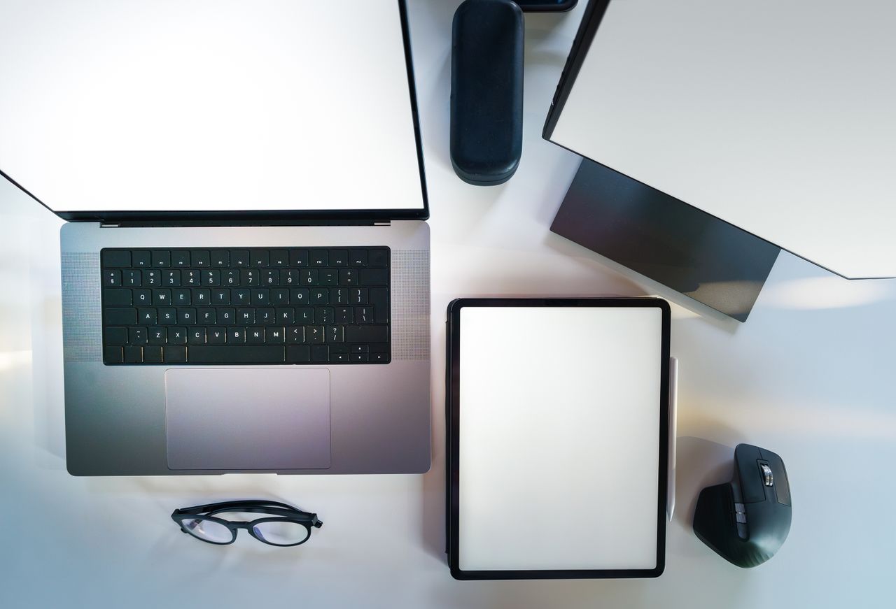 Vue de dessus d’un bureau de travail moderne et élégant, avec un ordinateur portable, une tablette et des accessoires.